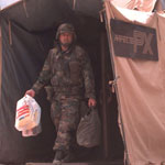 Soldier coming out of tent with bags on his hands