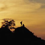 Two persons on top of a hill looking down.
